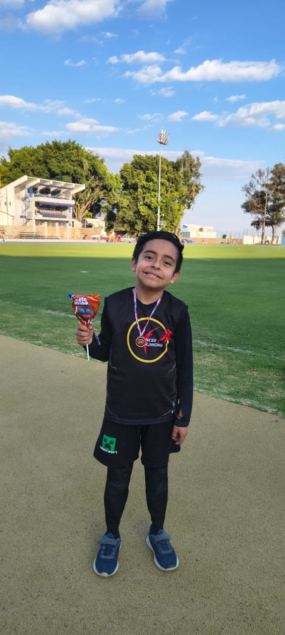 Alumno de Fit-Ness Running con su medalla en el campo